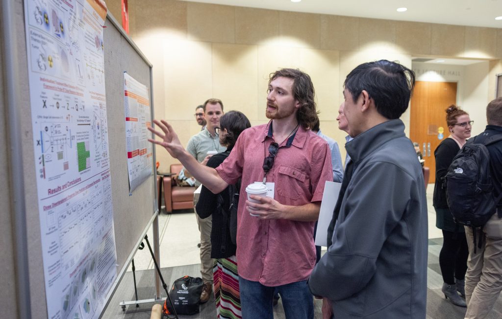 Multiple people looking at and discussing posters at the Precision Medicine Symposium 2025