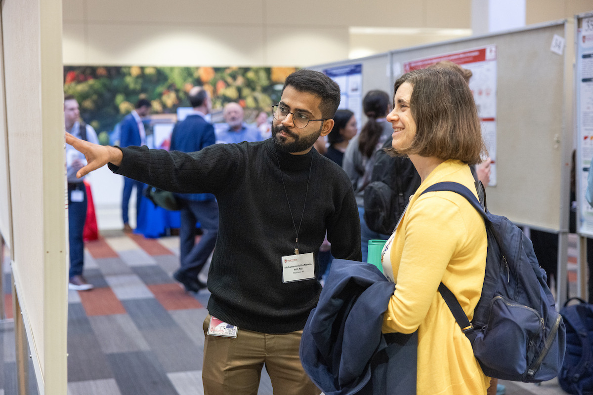 A Center for Precision Medicine lab member presents his poster to an affiliate member.